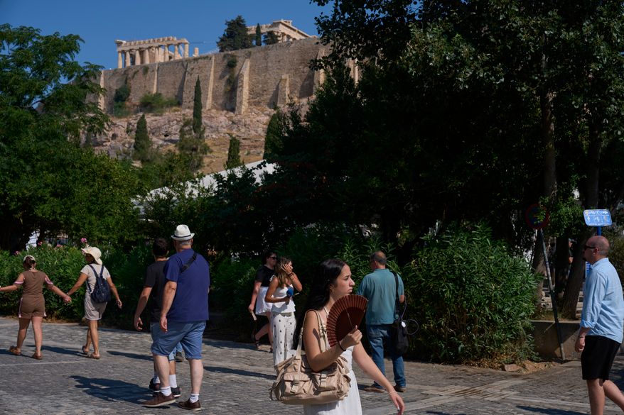 Tourists walk near the Acropolis in Athens, Greece, Tuesday, July 21, 2026, after two tourists were stabbed and injured nearby in an attack on a pedestrian street near the entrance to the archaeological site. (AP Photo/Petros Giannakouris)