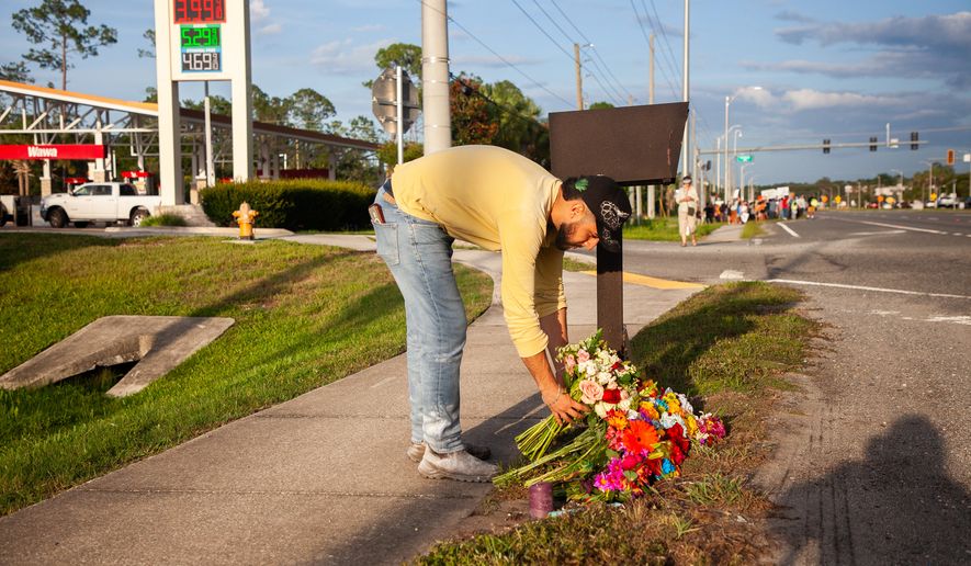 Edgar Olalde, of Jacksonville, who knew the victim from his store, lays a bouquet of flowers during a vigil for a Mexican man who was struck and killed by a tractor trailer while running from an encounter with Immigration and Customs Enforcements officers the day before, Wednesday, July 15, 2026, in St. Augustine, Fla. (AP Photo/Kelly Jordan)