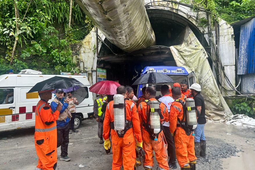 Members of the rescue team carry oxygen cylinders outside the entrance to an under-construction tunnel at a hydropower project in Samardung village, about 40 kilometers (25 miles) from Gangtok, India, Tuesday, July 21, 2026. (AP Photo)