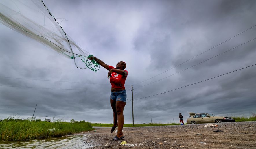 With skies darkening ahead of Tropical Storm Bertha, Latia Ancar practices her casting while she and a friend wait for the storm-driven tidal surge about 50 miles south of New Orleans on Wednesday, July 22, 2026, hoping it will bring more fish. (Chris Granger/The Times-Picayune/The New Orleans Advocate via AP)