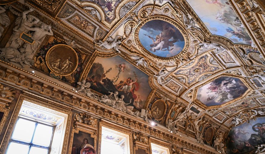 A visitor looks on during the reopening to the public of the Apollo Gallery, at the Louvre museum in Paris, Wednesday, July 22, 2026. (Lou Benoist/Pool Photo via AP)