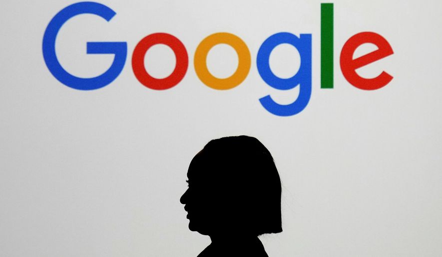 A woman walks by a giant screen displaying the Google logo at an event at the Paris Google Lab on the sidelines of the AI Action Summit in Paris, Feb. 9, 2025. (AP Photo/Thibault Camus, File)