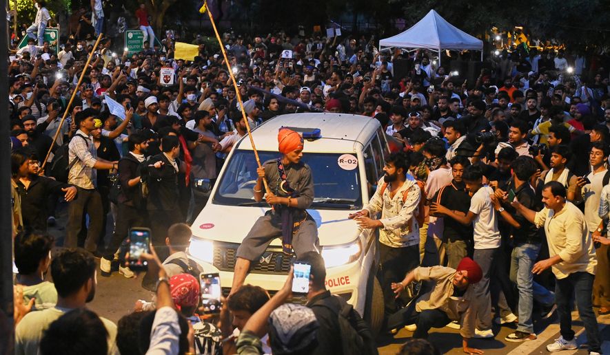 A protestor sits on the hood of a police car during a demonstration demanding educational reforms as part of the Cockroach Janta Party's ongoing protest movement in New Delhi, India, Wednesday, July 22, 2026. (AP Photo/Vipin)