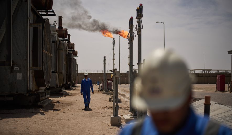 Workers walk in the Zubair oil field, whose operations have been reduced since the start of the Iran war, near Basra, Iraq, March 28, 2026. (AP Photo/Leo Correa, File)
