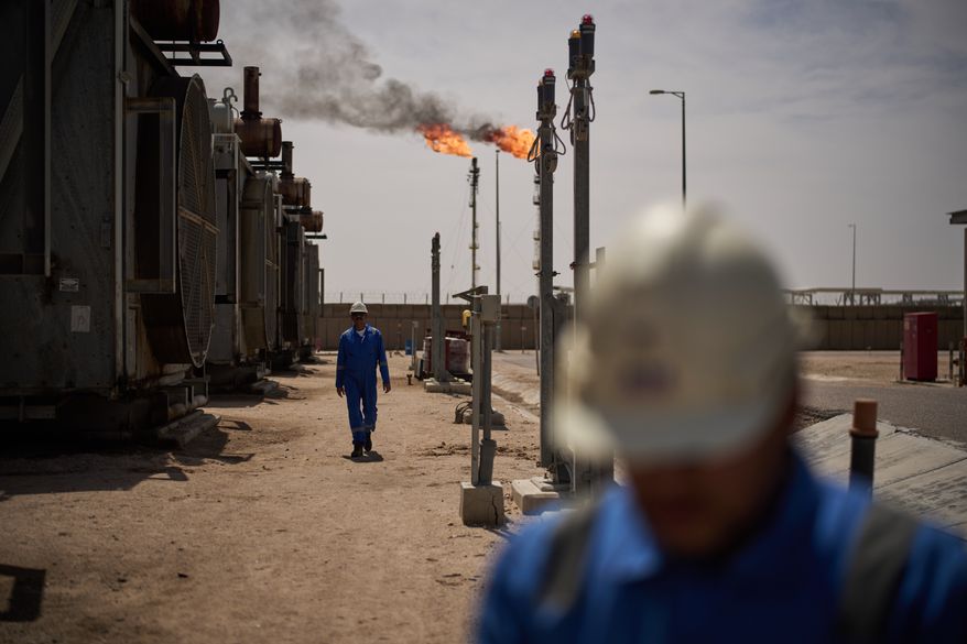 Workers walk in the Zubair oil field, whose operations have been reduced since the start of the Iran war, near Basra, Iraq, March 28, 2026. (AP Photo/Leo Correa, File)