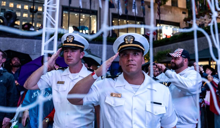 United States Navy personnel salute during the national anthem at a watch party in a fan village in New York's Rockefeller Center for a World Cup round of 16 soccer match between the United States and Belgium, Monday, July 6, 2026 in New York. (AP Photo/Adam Gray)