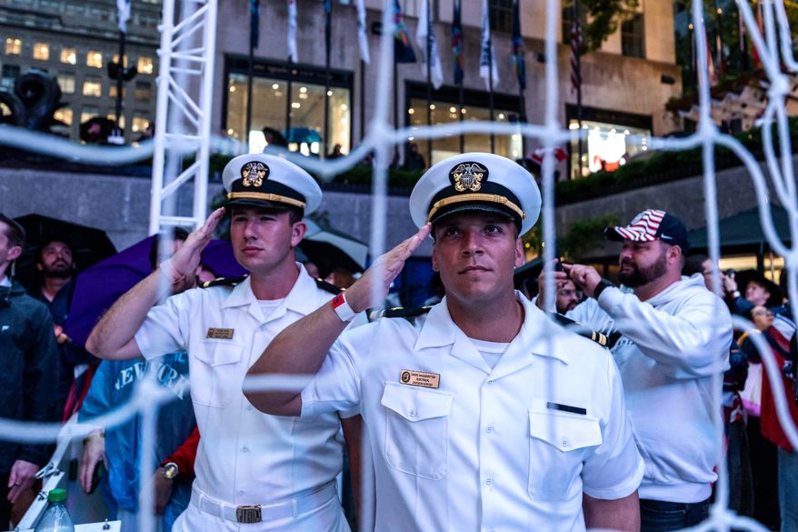 United States Navy personnel salute during the national anthem at a watch party in a fan village in New York's Rockefeller Center for a World Cup round of 16 soccer match between the United States and Belgium, Monday, July 6, 2026 in New York. (AP Photo/Adam Gray)