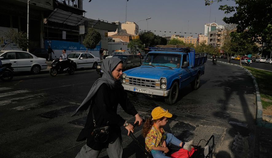 A woman crosses a street with a girl in downtown Tehran, Iran, Wednesday, July 22, 2026. (AP Photo/Vahid Salemi)