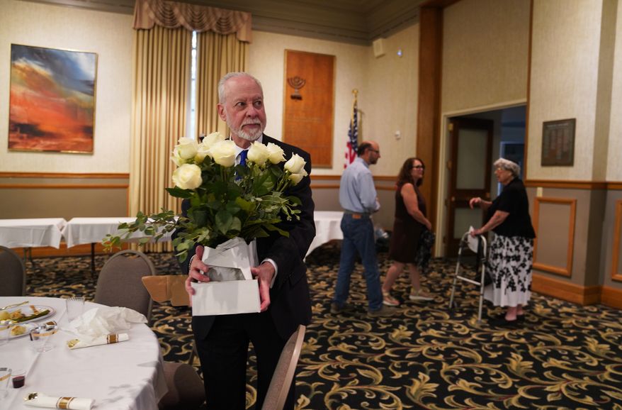 Rabbi Jeffrey Myers of the Tree of Life Congregation holds a bouquet of flowers while at his retirement dinner celebration on Friday, July 17, 2026, at Rodef Shalom Congregation in Pittsburgh. (AP Photo/Jessie Wardarski)