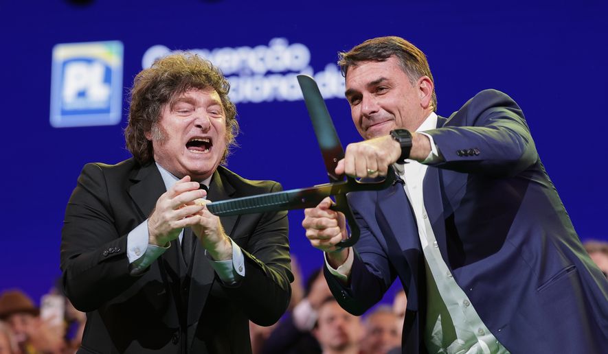 Brazilian Sen. Flavio Bolsonaro, right, handles an oversized pair of scissors, accompanied by Argentina's President Javier Milei during the Liberal Party convention where Bolsonaro was confirmed as the party's presidential candidate, in Sao Paulo, Saturday, July 25, 2026. (AP Photo/Ettore Chiereguini)