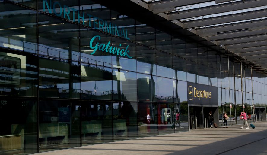 FILE - Passengers walk into the Departures entrance at the North Terminal of Gatwick Airport near Crawley, just south of London, on July 22, 2020. (AP Photo/Matt Dunham, File)