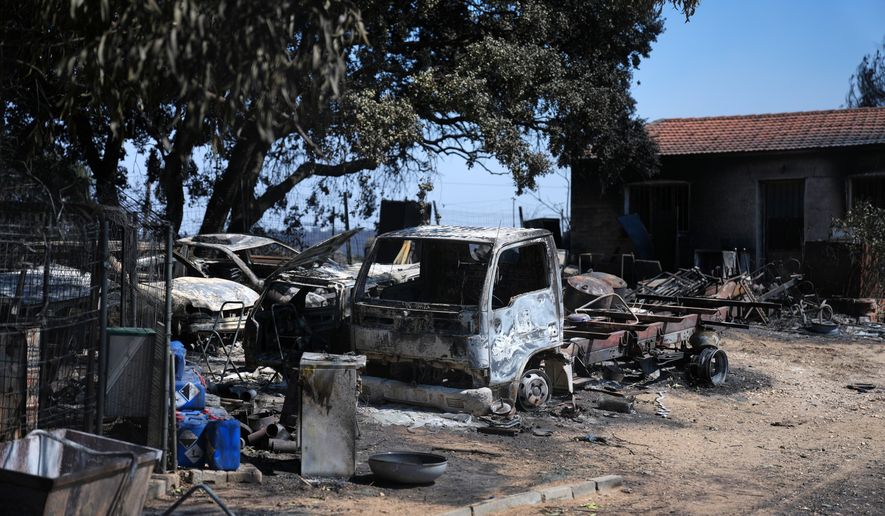 Burnt vehicles sit outside a charred house in Navas del Rey, west of Madrid, Spain, where wildfires have forced tens of thousands to be evacuated, Sunday, July 26, 2026. (AP Photo/Manu Fernandez)