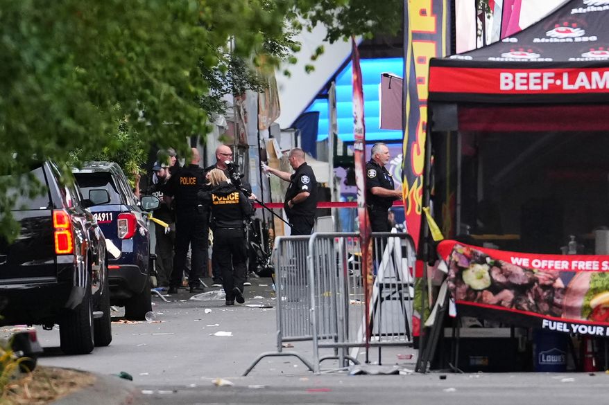A crime scene photographer arrives as law enforcement examines the scene following a shooting at Seattle Center during the Bite of Seattle food festival Sunday, July 26, 2026, in Seattle. (AP Photo/Lindsey Wasson)