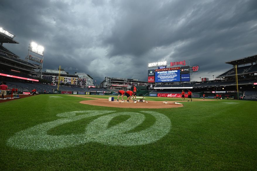The Washington Nationals grounds crew works on the field as the baseball game between the Washington Nationals and the Toronto Blue Jays is being delayed due to inclement weather in the area, Tuesday, July 28, 2026, in Washington. (AP Photo/Nick Wass)