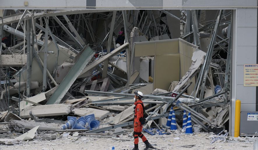 A rescue worker walks in front of AEON Mall, which was damaged by an explosion following an earthquake, is seen in Kashima, Kumamoto Prefecture, southern Japan, Wednesday, July 29, 2026. (AP Photo/Hiro Komae)
