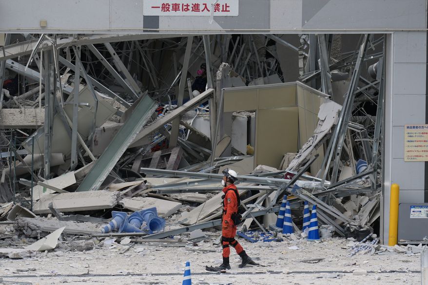 A rescue worker walks in front of AEON Mall, which was damaged by an explosion following an earthquake, is seen in Kashima, Kumamoto Prefecture, southern Japan, Wednesday, July 29, 2026. (AP Photo/Hiro Komae)
