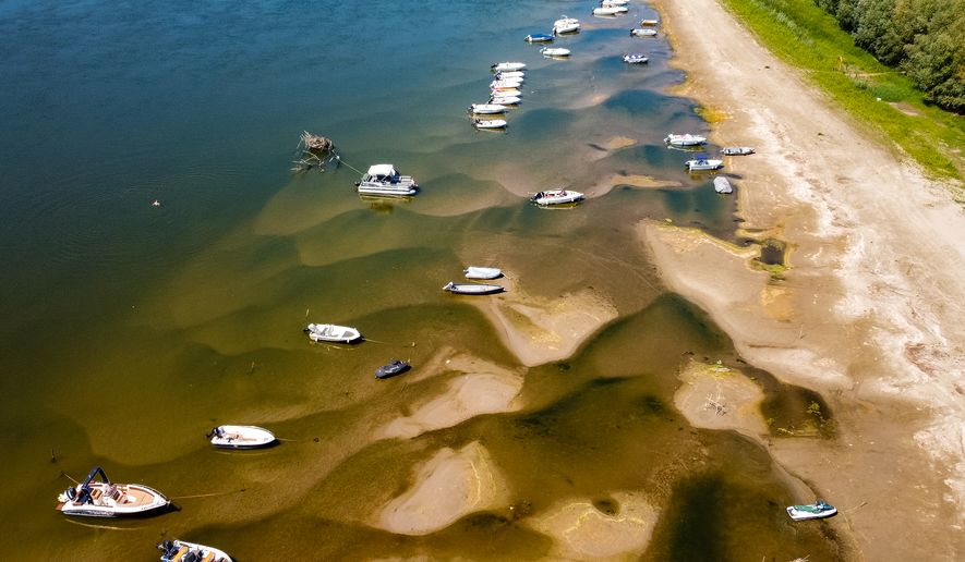 Boats sit on a bank of the Danube River where usually submerged areas are exposed due to extremely low water levels following an extended period of drought in Islaz, Romania, Wednesday, July 29, 2026. (AP Photo/Nicolae Dumitrache)