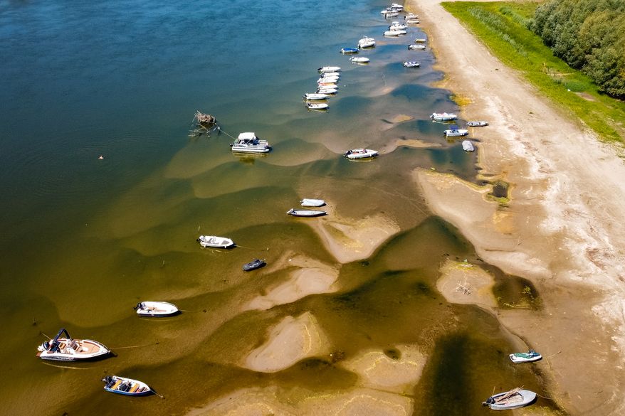 Boats sit on a bank of the Danube River where usually submerged areas are exposed due to extremely low water levels following an extended period of drought in Islaz, Romania, Wednesday, July 29, 2026. (AP Photo/Nicolae Dumitrache)