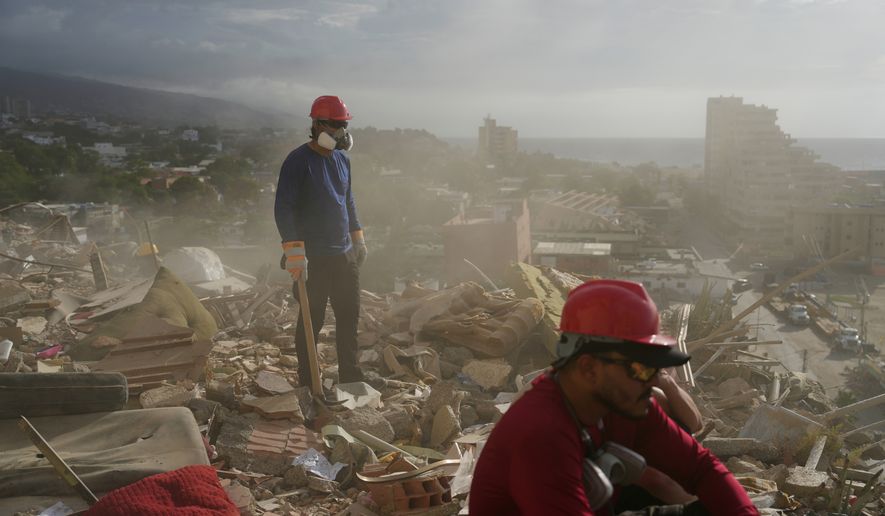 FILE - Rescue workers and volunteers search through the rubble of a building collapsed during the earthquakes in La Guaira, Venezuela, July 6, 2026. (AP Photo/Ariana Cubillos, File)