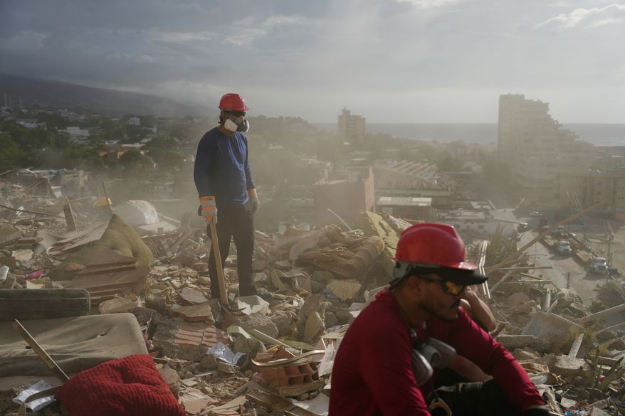 FILE - Rescue workers and volunteers search through the rubble of a building collapsed during the earthquakes in La Guaira, Venezuela, July 6, 2026. (AP Photo/Ariana Cubillos, File)