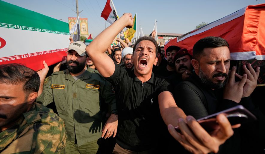 Mourners carry coffins draped in the Iranian flag, left, and the Iraqi flag, right, during a group funeral for Iranian advisers and Popular Mobilization Forces fighters killed in airstrikes on bases belonging to Iraq's Popular Mobilization Forces, which includes Iran-backed groups, in Mosul, Iraq, Wednesday, July 29, 2026. (AP Photo/Hadi Mizban)
