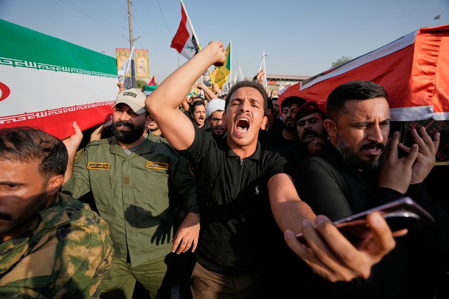 Mourners carry coffins draped in the Iranian flag, left, and the Iraqi flag, right, during a group funeral for Iranian advisers and Popular Mobilization Forces fighters killed in airstrikes on bases belonging to Iraq's Popular Mobilization Forces, which includes Iran-backed groups, in Mosul, Iraq, Wednesday, July 29, 2026. (AP Photo/Hadi Mizban)