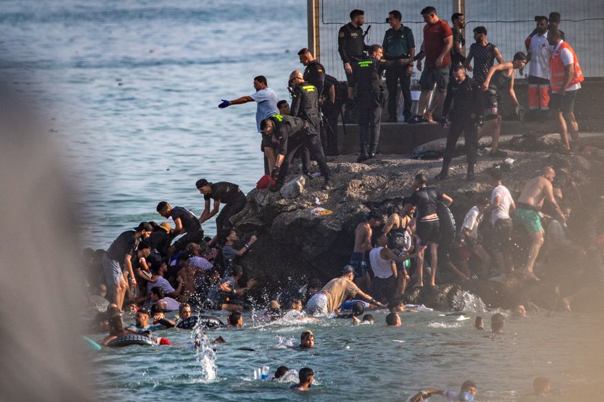 Migrants try to cross from Morocco into the Spanish enclave of Ceuta, Thursday, July 30, 2026. (AP Photo/Antonio Sempere)