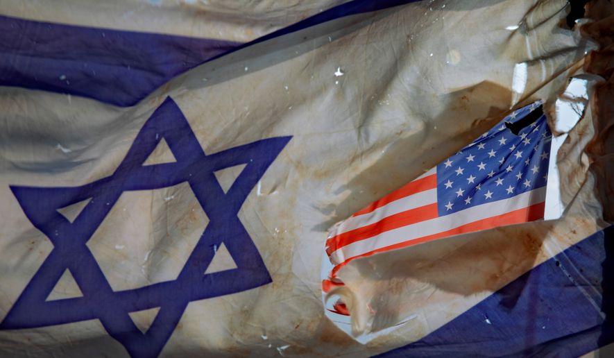 A U.S. flag is seen through a hole torn in an Israel national flag, as they wave in the wind at a horse ranch, near the southern Israeli town of Sderot, Friday, Nov. 20, 2020. (AP Photo/Oded Balilty, File)
