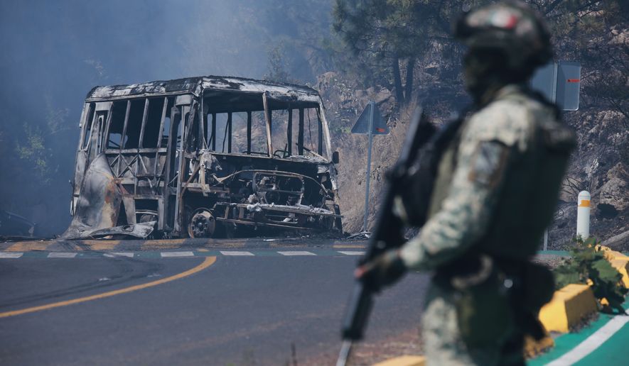 FILE - A soldier stands guard by a charred vehicle after it was set on fire in Cointzio, Michoacán state, Mexico, Feb. 22, 2026, following the death of the leader of the Jalisco New Generation Cartel, Nemesio Oseguera, also known as "El Mencho." (AP Photo/Armando Solis, File)