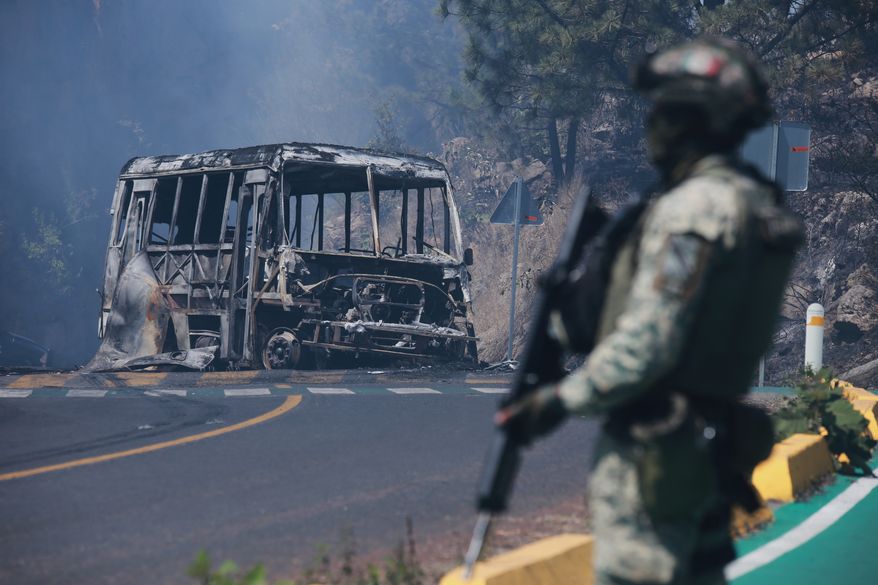 FILE - A soldier stands guard by a charred vehicle after it was set on fire in Cointzio, Michoacán state, Mexico, Feb. 22, 2026, following the death of the leader of the Jalisco New Generation Cartel, Nemesio Oseguera, also known as "El Mencho." (AP Photo/Armando Solis, File)