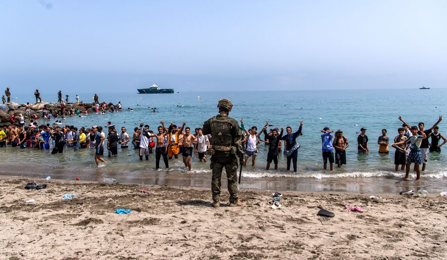 Spanish army soldiers block access to the beach for people crossing from Morocco into the Spanish enclave of Ceuta, Friday, July 31, 2026. (AP Photo/Antonio Sempere)