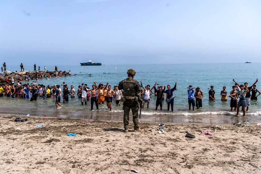 Spanish army soldiers block access to the beach for people crossing from Morocco into the Spanish enclave of Ceuta, Friday, July 31, 2026. (AP Photo/Antonio Sempere)
