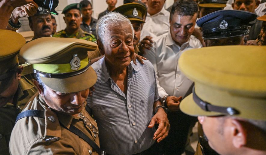 Sri Lankan police officials escort former Defense Ministry Secretary Hemasiri Fernando, center left, and former Police Chief Pujith Jayasundara, center right, outside a court in Colombo, Sri Lanka, Friday, July 31, 2026. (AP Photo)