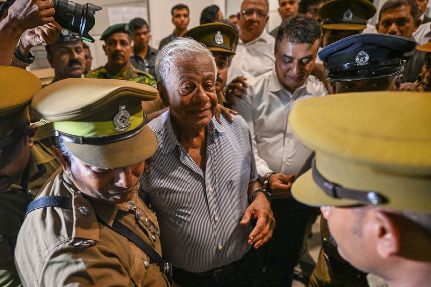 Sri Lankan police officials escort former Defense Ministry Secretary Hemasiri Fernando, center left, and former Police Chief Pujith Jayasundara, center right, outside a court in Colombo, Sri Lanka, Friday, July 31, 2026. (AP Photo)