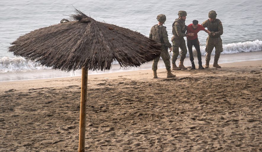 Spanish army soldiers assist a migrant who swam from Morocco to the Spanish enclave of Ceuta, Saturday, Aug. 1, 2026. (AP Photo/Antonio Sempere)