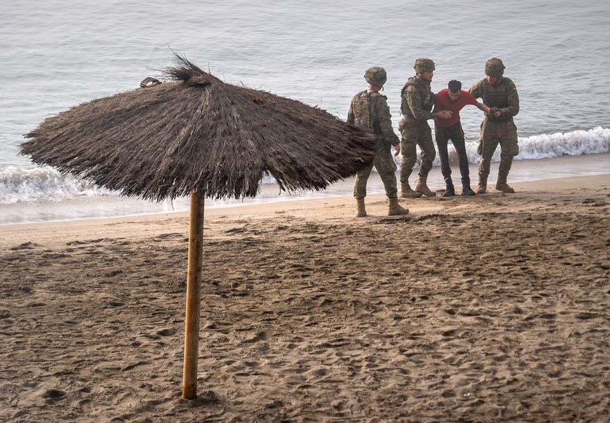 Spanish army soldiers assist a migrant who swam from Morocco to the Spanish enclave of Ceuta, Saturday, Aug. 1, 2026. (AP Photo/Antonio Sempere)