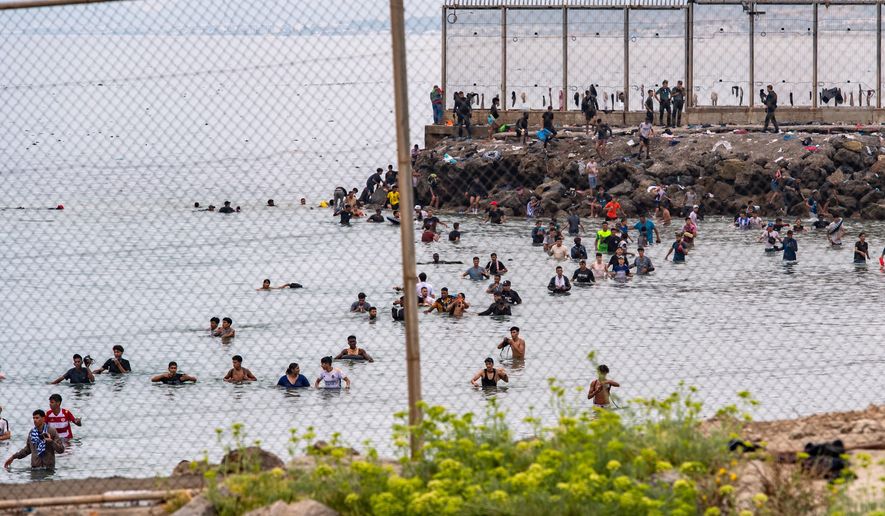 Migrants try to cross from Morocco into the Spanish enclave of Ceuta, Friday, July 31, 2026. (AP Photo/Antonio Sempere)