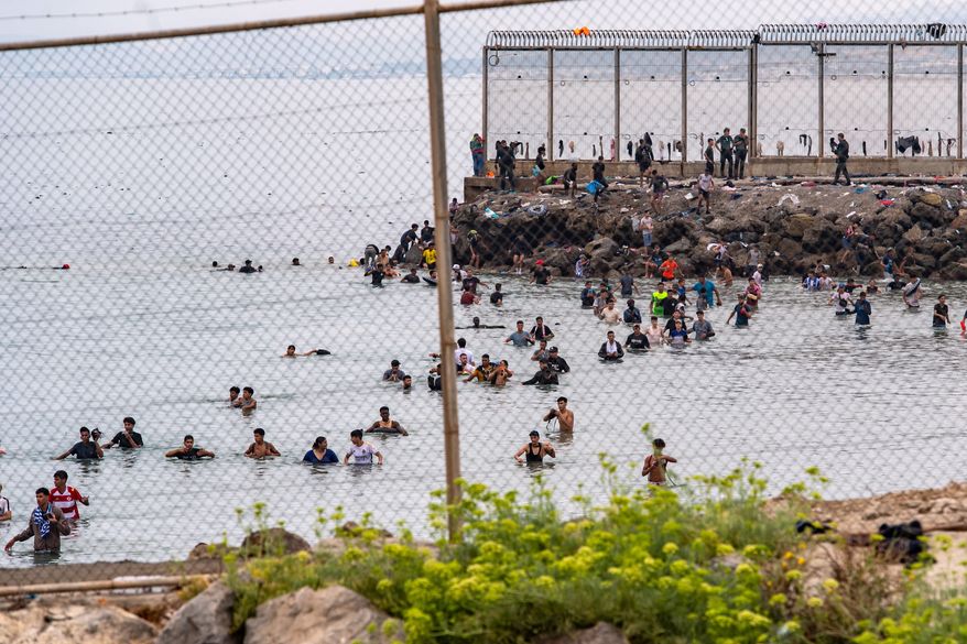 Migrants try to cross from Morocco into the Spanish enclave of Ceuta, Friday, July 31, 2026. (AP Photo/Antonio Sempere)