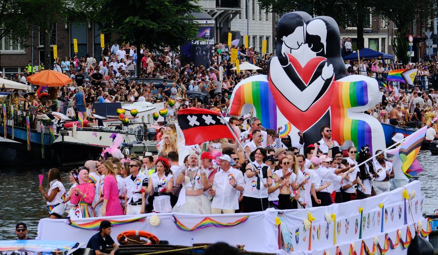 People line the Dutch capital's historic canals Saturday, Aug. 1, 2026, to watch the Canal Parade, the most popular event of the Pride Amsterdam festival that attracts tens of thousands of visitors to the city. (AP Photo/Patrick Post)