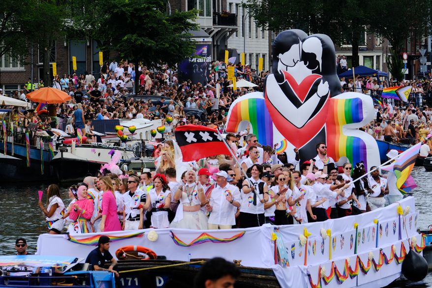 People line the Dutch capital's historic canals Saturday, Aug. 1, 2026, to watch the Canal Parade, the most popular event of the Pride Amsterdam festival that attracts tens of thousands of visitors to the city. (AP Photo/Patrick Post)