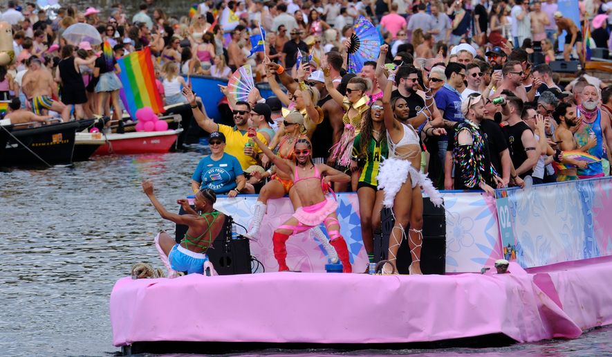 People celebrate atop a boat on one of the Dutch capital's historic canals, Saturday, Aug. 1, 2026, during the Canal Parade, the most popular event of the Pride Amsterdam festival. (AP Photo/Patrick Post)