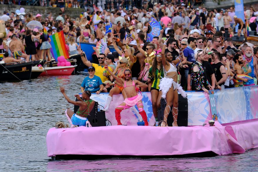 People celebrate atop a boat on one of the Dutch capital's historic canals, Saturday, Aug. 1, 2026, during the Canal Parade, the most popular event of the Pride Amsterdam festival. (AP Photo/Patrick Post)