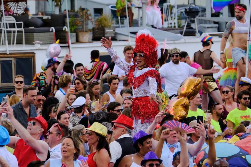 People celebrate atop a boat on one of the Dutch capital's historic canals, Saturday, Aug. 1, 2026, during the Canal Parade, the most popular event of the Pride Amsterdam festival. (AP Photo/Patrick Post)