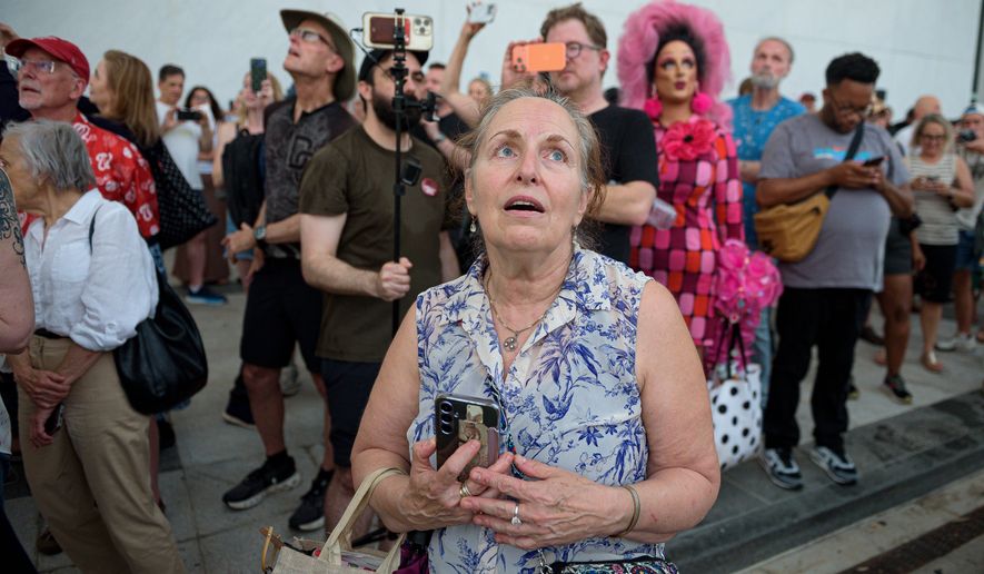 FILE - A crowd sings, "God Bless America," as they wait to watch the removal of President Donald Trump's name from the John F. Kennedy Center for the Performing Arts in Washington, June 12, 2026. (AP Photo/Cliff Owen, File)