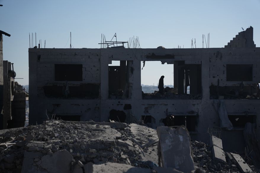 A Palestinian woman inspects a destroyed building following an Israeli airstrike in Deir al-Balah, central Gaza Strip, Sunday, July 19, 2026. (AP Photo/Abdel Kareem Hana)