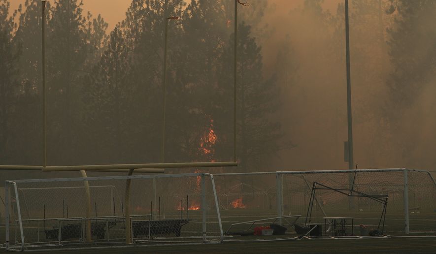 Old Trails Fire burns near Dwight Merkel Sports Complex, Saturday, Aug. 1, 2026, in Spokane, Wash. (AP Photo/Young Kwak)