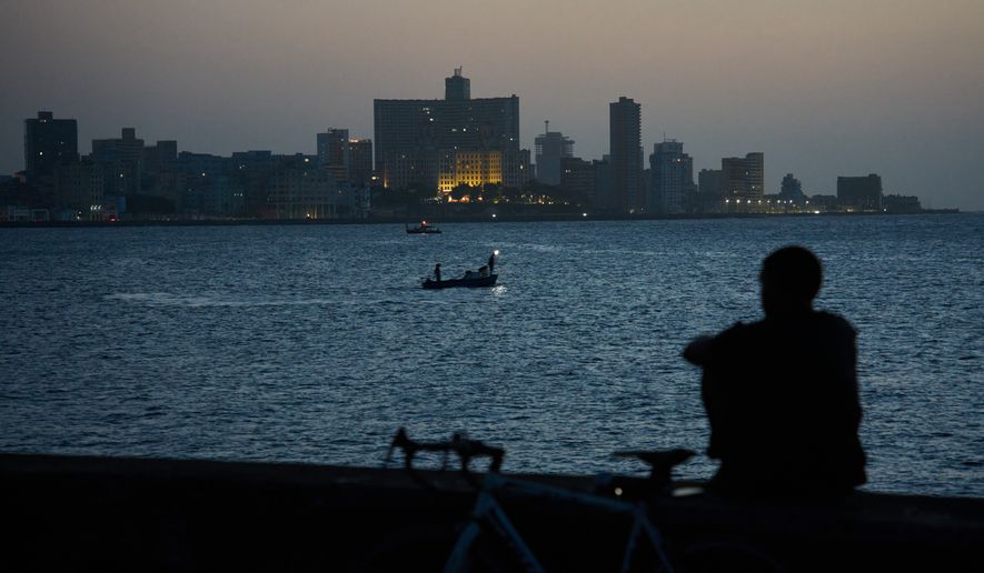 A man sits on the Malecón seawall after sunset during a blackout in Havana, Cuba, Tuesday, July 14, 2026. (AP Photo/Ramon Espinosa)