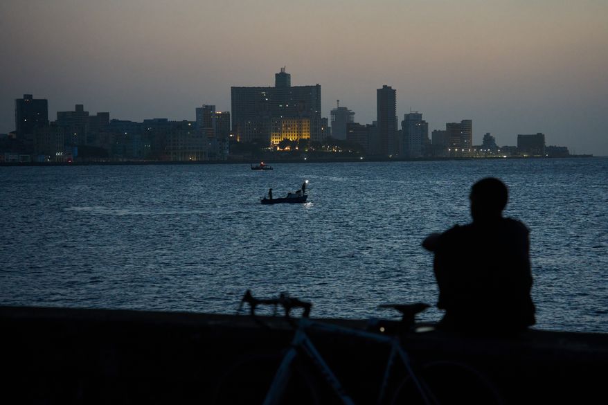 A man sits on the Malecón seawall after sunset during a blackout in Havana, Cuba, Tuesday, July 14, 2026. (AP Photo/Ramon Espinosa)