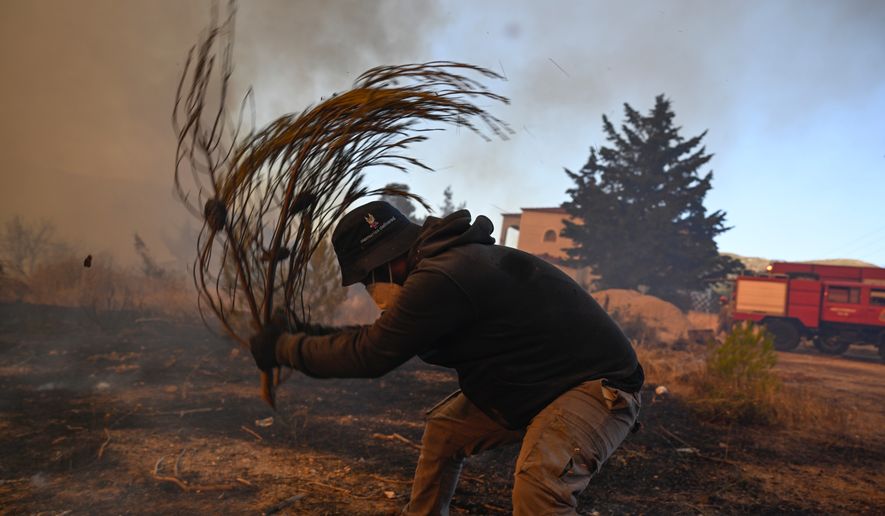 A volunteer tries to extinguish small flames during a wildfire near Porto Germeno, northwest of Athens, Greece, Sunday, Aug. 2, 2026. (AP Photo/Michael Varaklas)