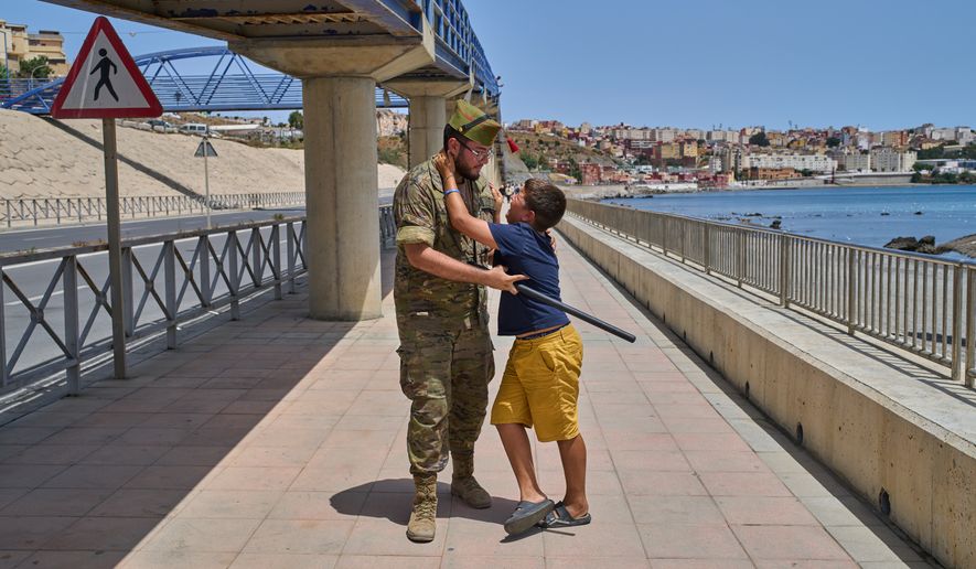 A 12-year-old unaccompanied minor who crossed into Spain is escorted by a Spanish soldier to the Spain-Morocco border as the child begs not to be sent back to Morocco from the Spanish enclave of Ceuta, Monday, Aug. 3, 2026. The forced deportation of the unaccompanied minor was stopped by a high-ranking official a few meters before the child reached the border after residents and journalists said the migrant was a minor. (AP Photo/Bernat Armangue)